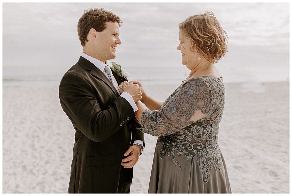 mom pinning boutonniere on groom