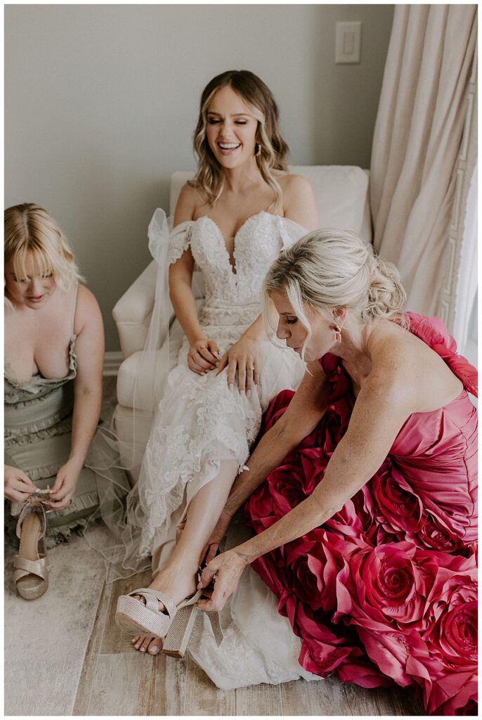 mom helping bride with shoes