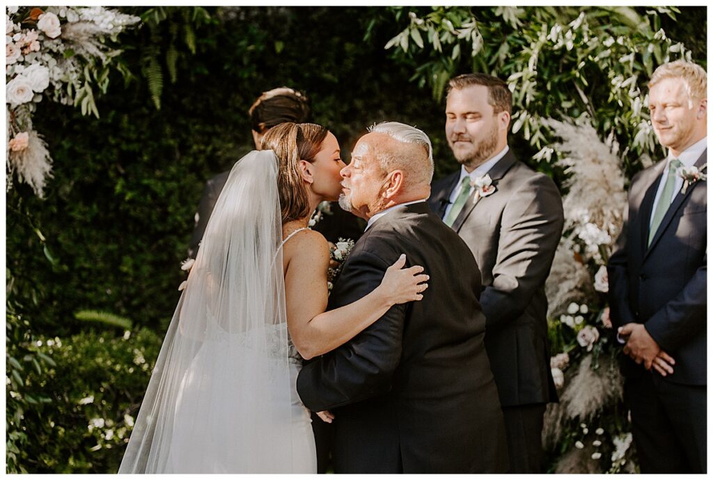Father of bride kissing her cheek