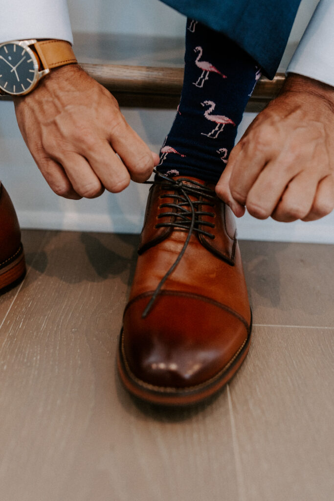 groom tying shoe, showing his pink flamingo socks