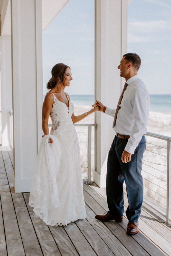 couple are holding hands on the balcony of the beach house