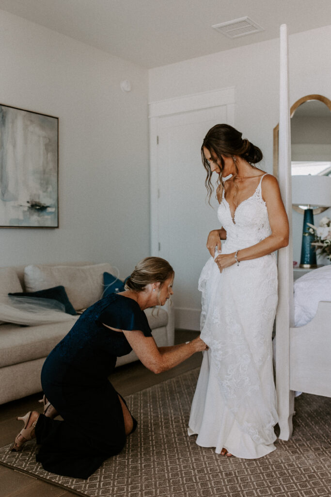 mom helping bride with wedding dress