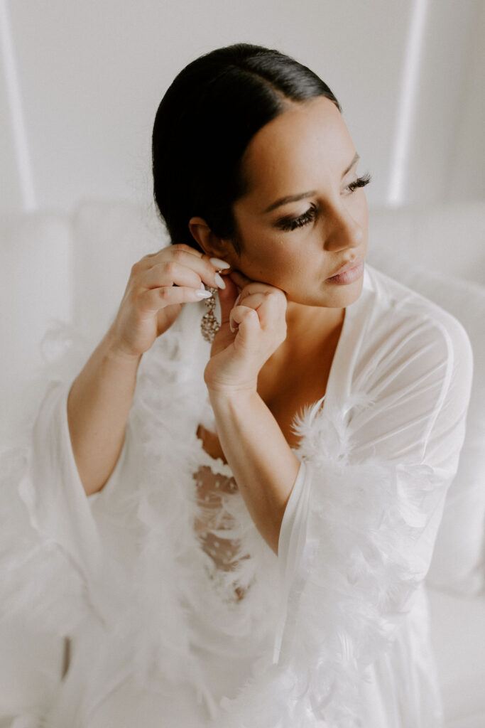 Bride putting on earrings