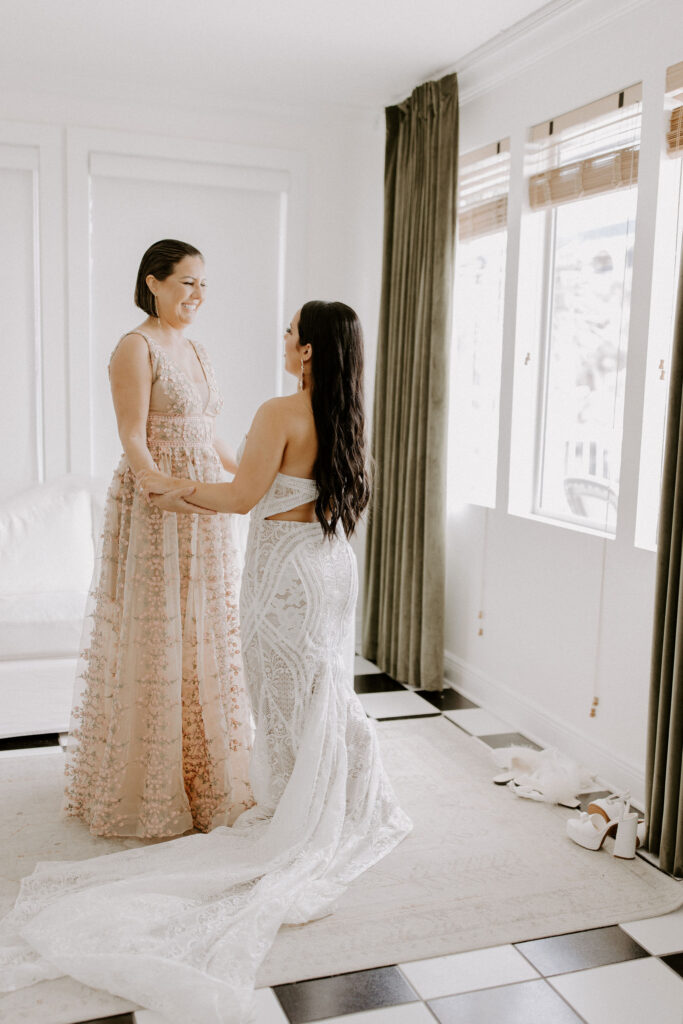 Bride and mom holding arms looking at each other