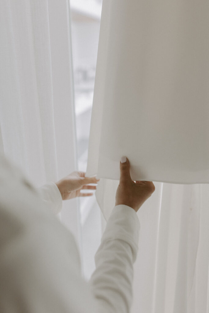 Closeup of brides hands on wedding gown
