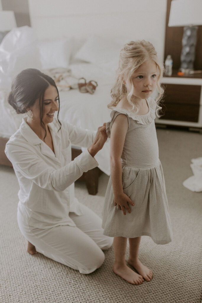 bride buttoning flower girl's dress