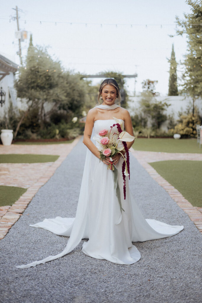A bride standing in the courtyard at the Supposey Warehouse & Gardens wedding venue, holding a bouquet.