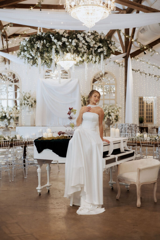 A bride and groom sitting on the grand piano at the Supposey Warehouse & Gardens wedding venue. 