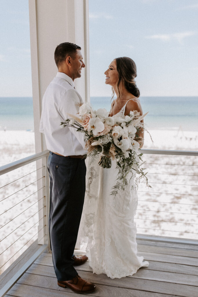 bride and groom on balcony of beach house