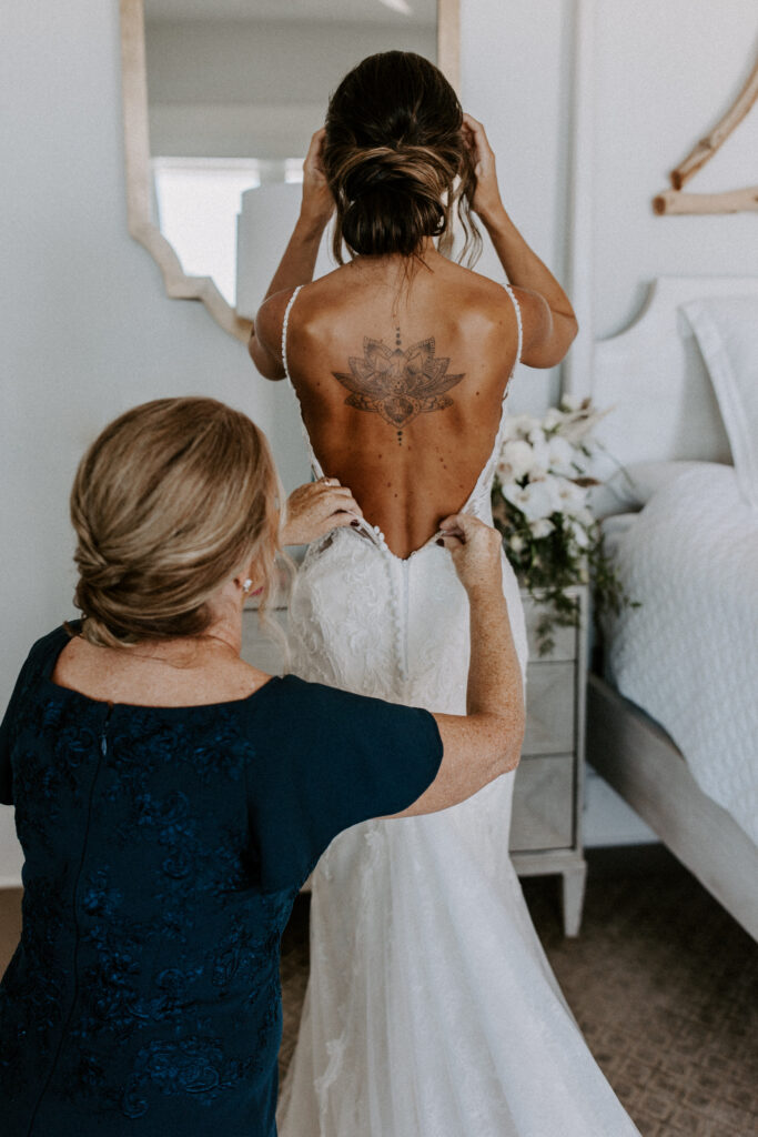 brides mom zipping up wedding gown