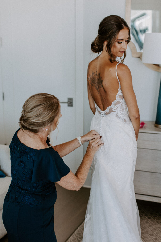 mom zipping up brides dress