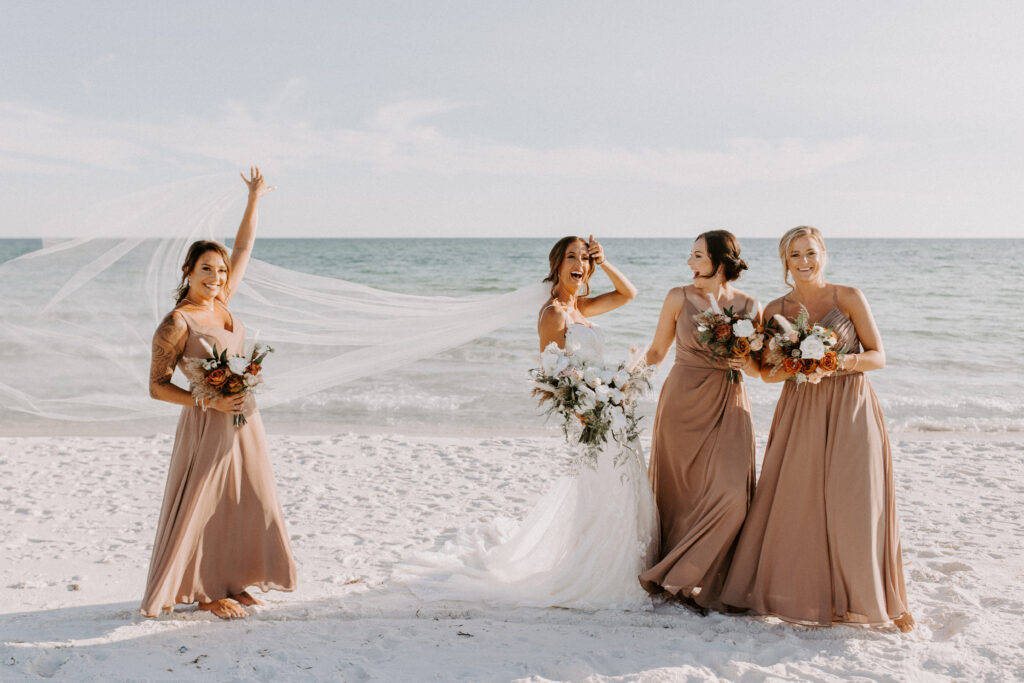 bride with bridesmaids, veil is flowing in the wind