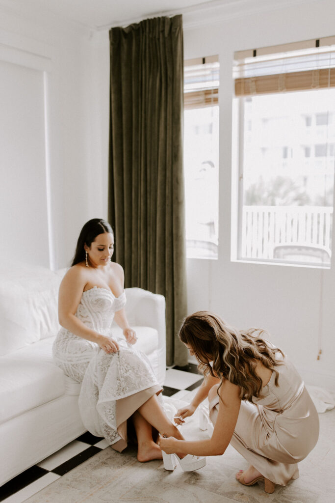 Maid of honor helping bride put on shoes