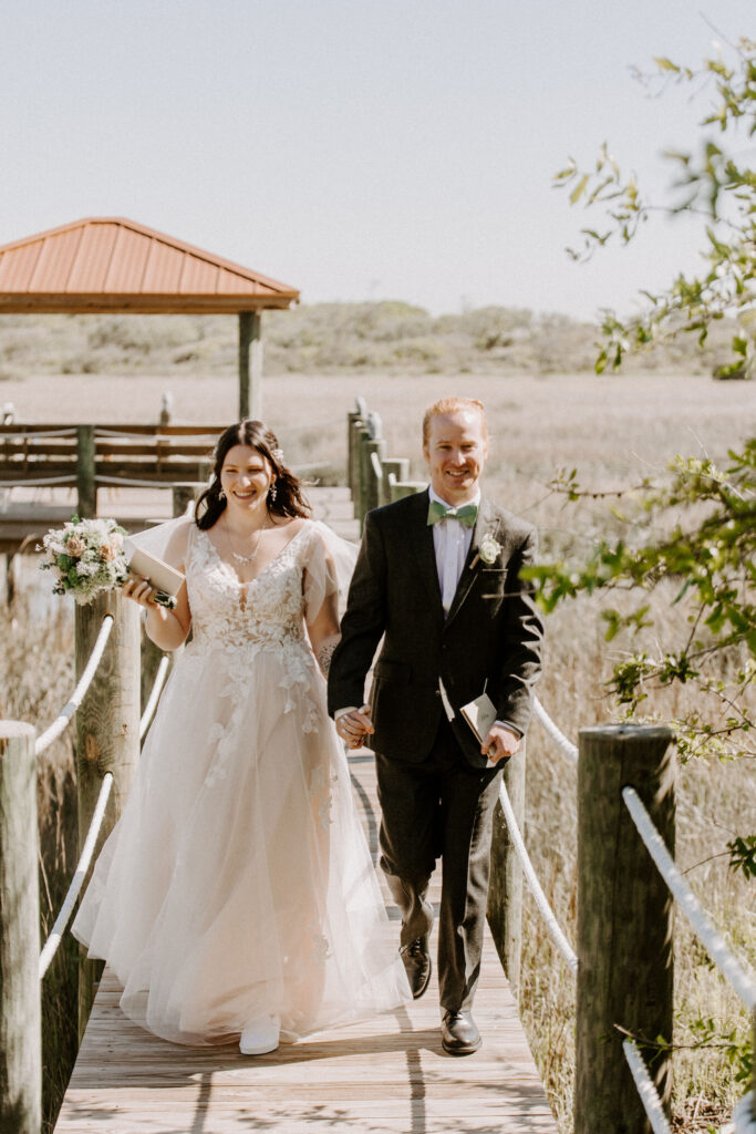 Couple walking on a boardwalk after their wedding ceremony